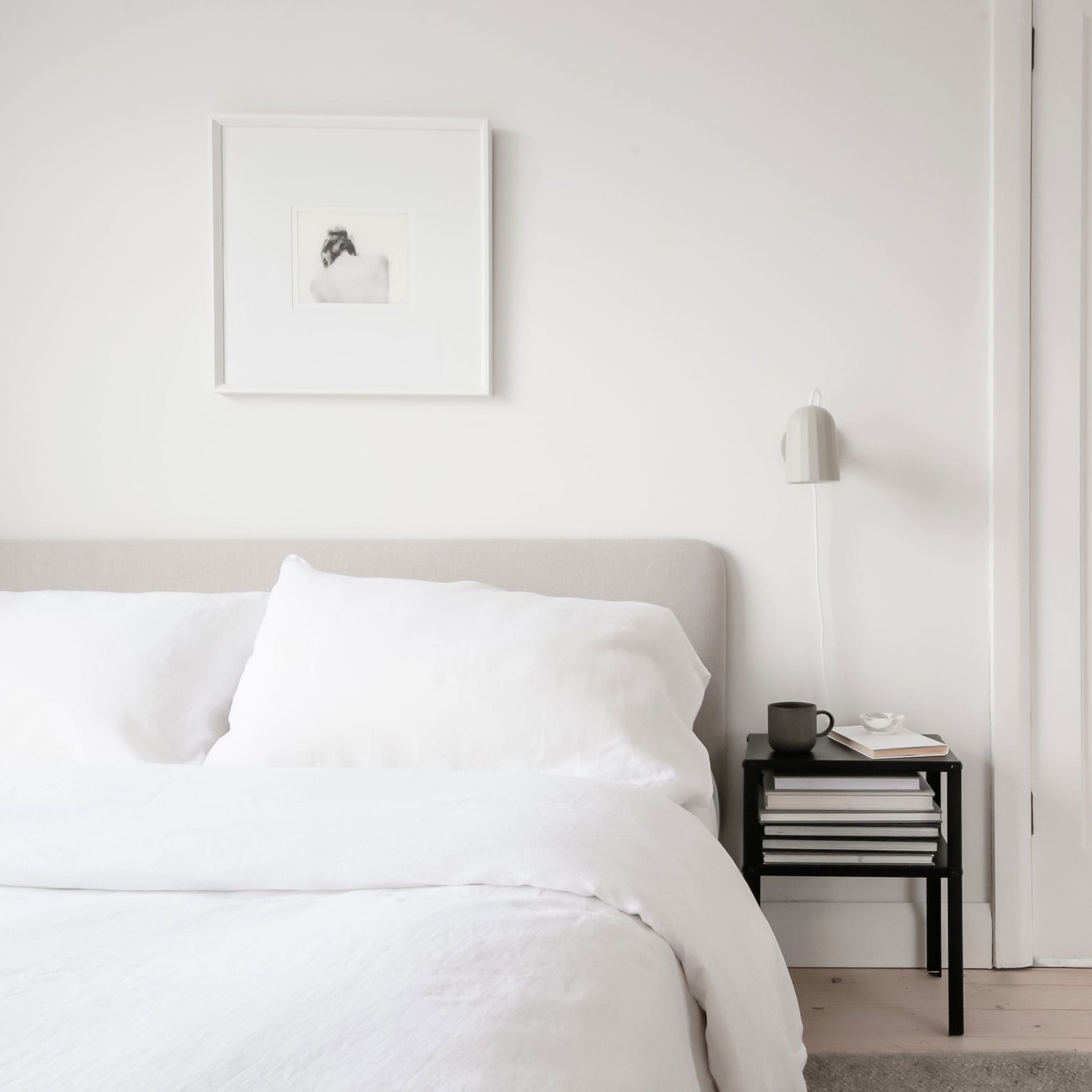White linen bedding set on a bed in a white bedroom. Scooms