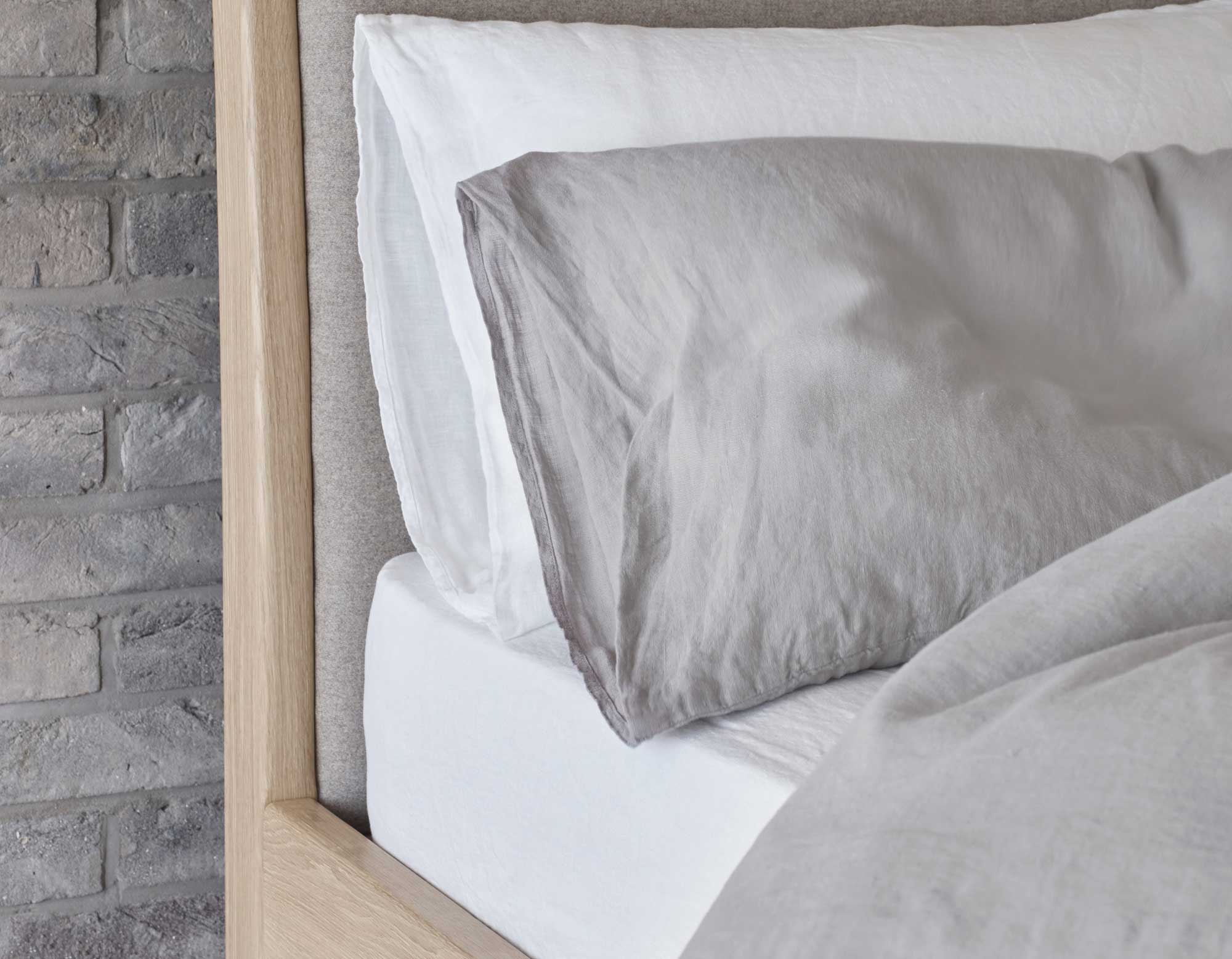 White linen fitted sheet on bed with grey and white pillowcases